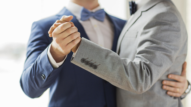 people, homosexuality, same-sex marriage and love concept - close up of happy male gay couple holding hands and dancing on wedding