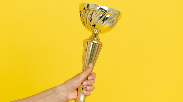 hand holding trophy on yellow background